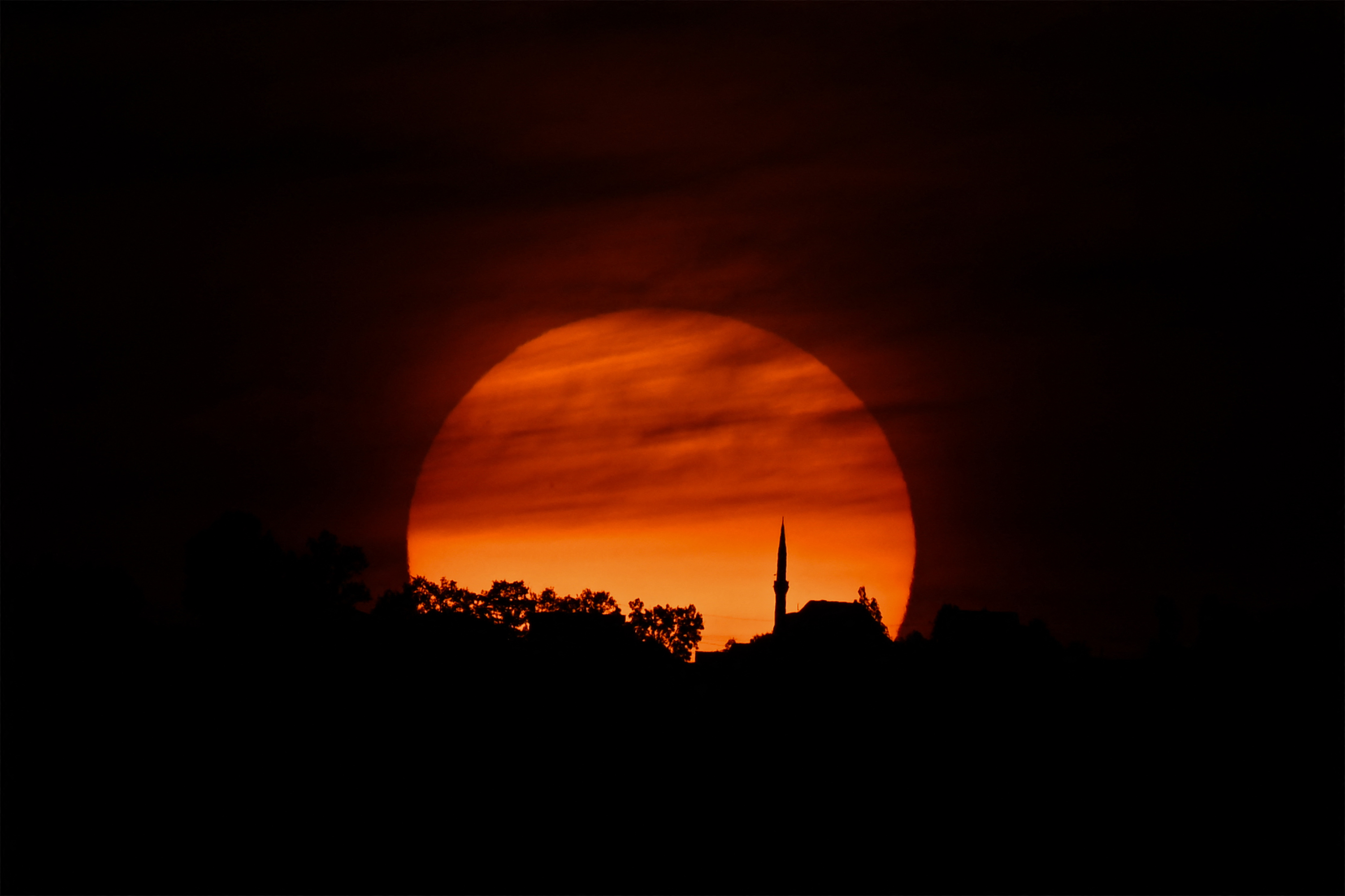 O sol se põe durante um eclipse solar parcial na vila de Rashincë, no município de Shtime, no sul do Kosovo.