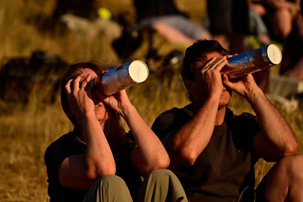 Pessoas observam o eclipse solar parcial através de câmeras pinhole caseiras no parque paisagístico Halde Hoheward, em Herten, no oeste da Alemanha.