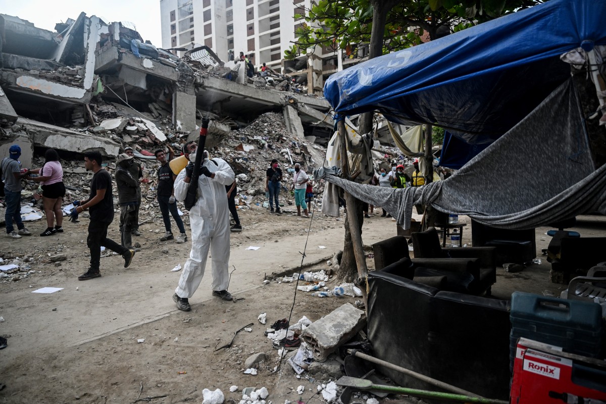 Um homem aplica pesticidas perto dos escombros de um prédio em Caraballeda, Venezuela, em 22 de julho de 2026, quase um mês após os terremotos de 24 de junho