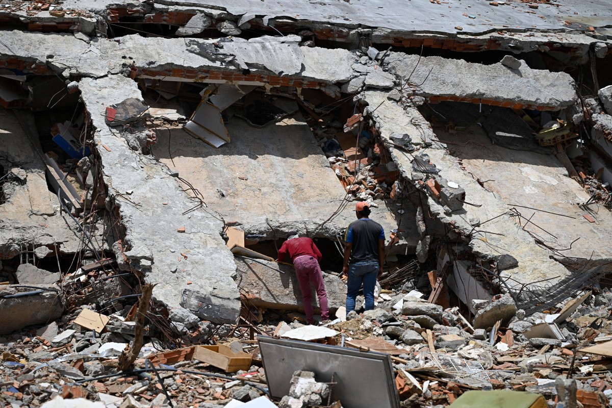 Pessoas buscam sucata nos escombros do edifício La Mar Suite, em Tucacas, Venezuela, em 22 de julho de 2026, quase um mês após os terremotos de 24 de junho