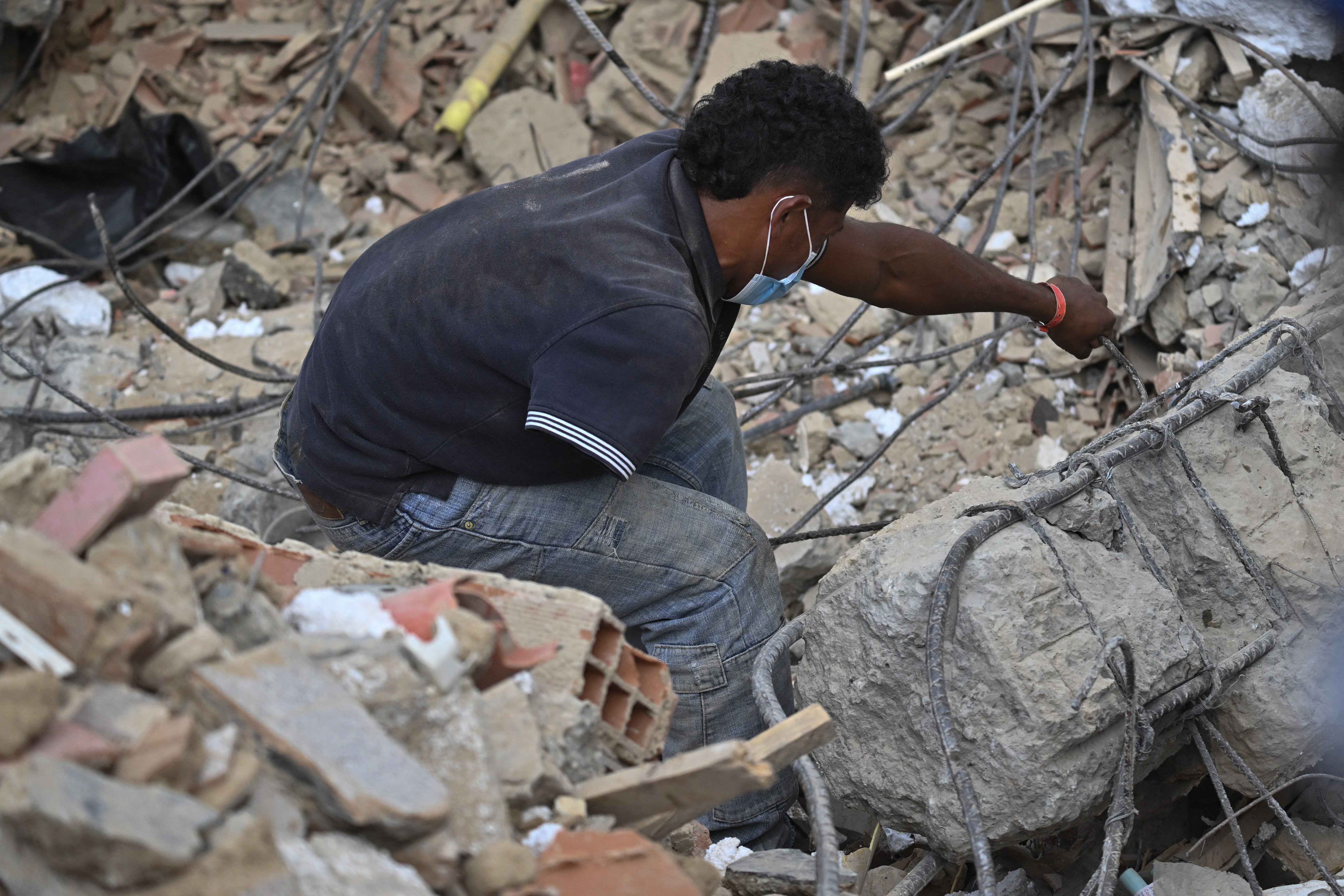 Um homem com apenas um braço procura por corpos entre os escombros de um prédio em Caraballeda, na Venezuela, em 22 de julho de 2026, quase um mês após os terremotos de 24 de junho