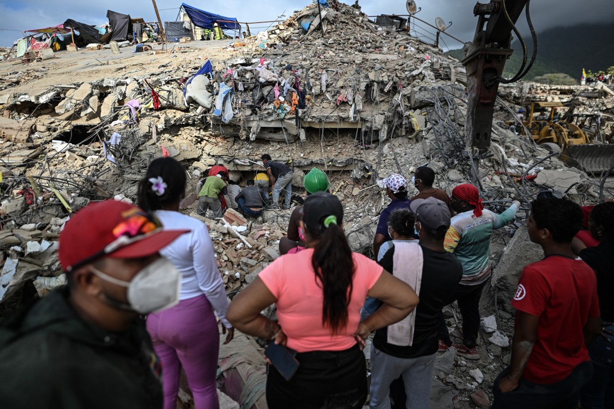 Pessoas buscam corpos em meio aos escombros de um prédio em Caraballeda, na Venezuela, em 22 de julho de 2026, quase um mês após os terremotos de 24 de junho
