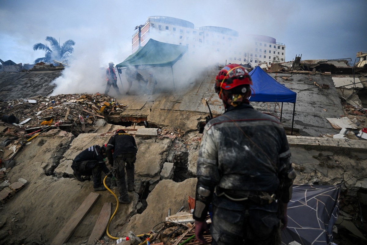 Uma equipe de resgate trabalha enquanto um homem aplica pesticidas sobre os escombros de um prédio em Caraballeda, Venezuela, em 22 de julho de 2026 — quase um mês após os terremotos de 24 de junho.