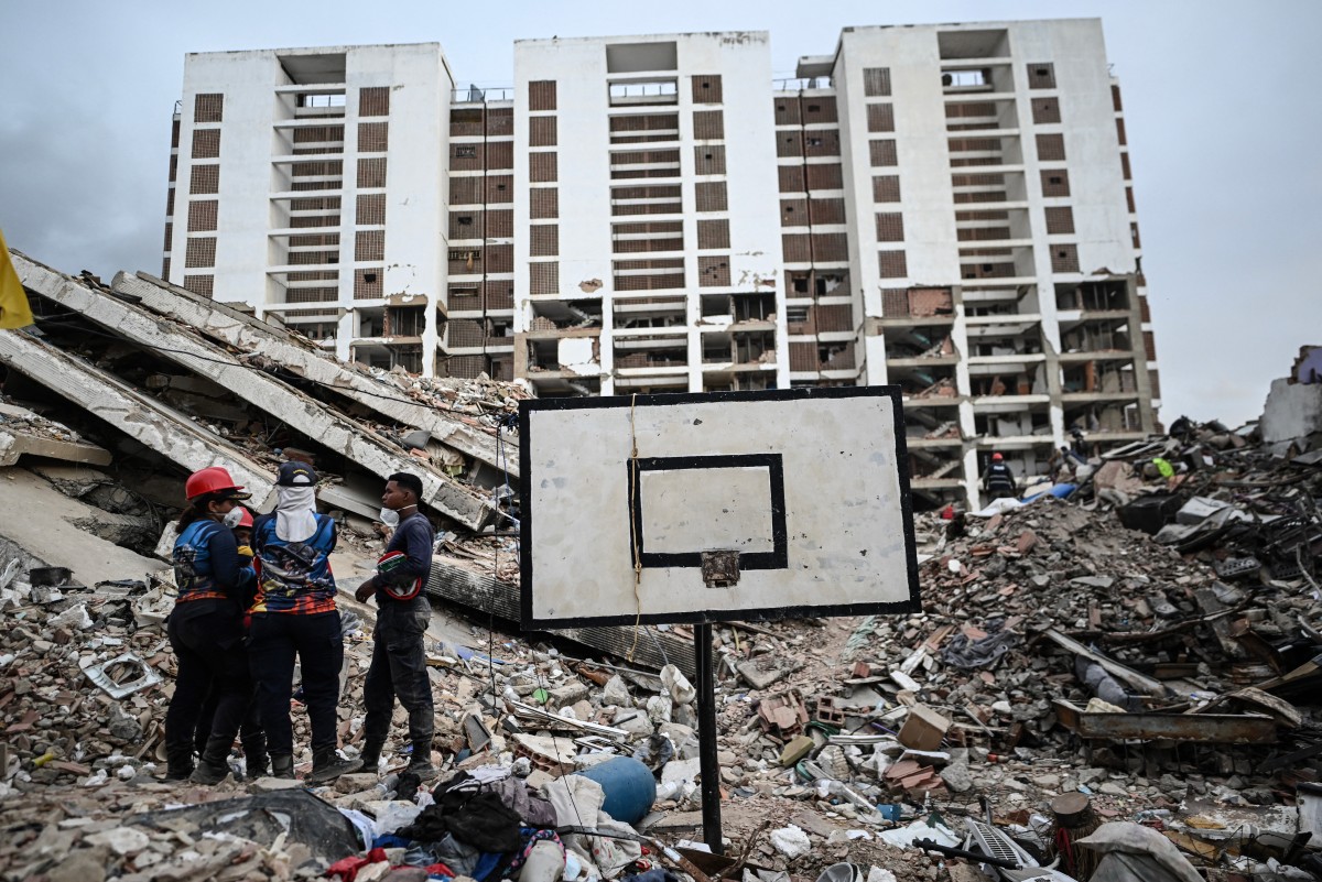 Voluntários conversam enquanto participam das buscas por corpos entre os escombros de um edifício do programa Obras del Poder Popular (OPP) em Caraballeda, Venezuela, em 22 de julho de 2026 — quase um mês após os terremotos de 24 de junho