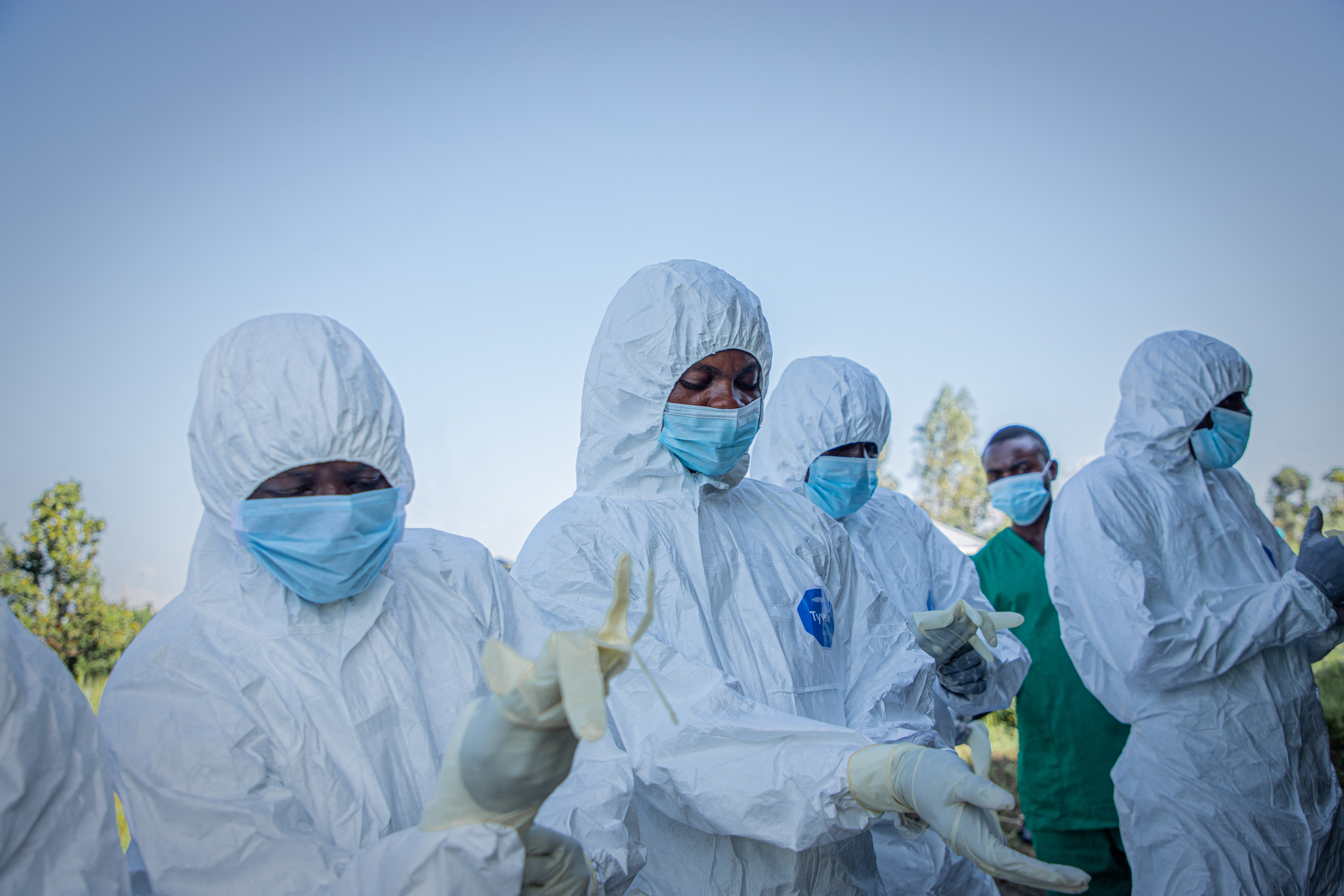 Voluntários vestem seus equipamentos de proteção individual antes de recolher o corpo de uma criança de 3 anos, com suspeita de morte por doença causada pelo vírus Ebola, em Bunia, em 11 de junho de 2026. Um surto de Ebola na República Democrática do Congo matou 2.011 pessoas de um total de 4.381 casos confirmados do vírus, informaram autoridades congolesas na terça-feira.