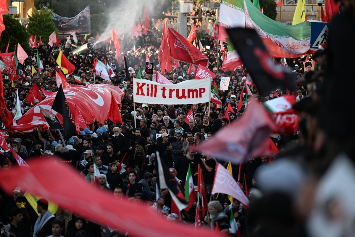 Multidões de pessoas em luto reúnem-se em uma rua antes do cortejo fúnebre do falecido Líder Supremo do Irã, Ali Khamenei, e de membros de sua família, antes de seu sepultamento no Santuário do Imam Reza — o local de culto mais venerado do Irã —, em Mashhad, em 9 de julho de 2026. Clamando por vingança e rejeitando qualquer acordo com o Ocidente, iranianos leais à República Islâmica enfrentaram um calor intenso em 9 de julho para se reunir em massa para o sepultamento do Líder Supremo Ali Khamenei em sua cidade natal, Mashhad.