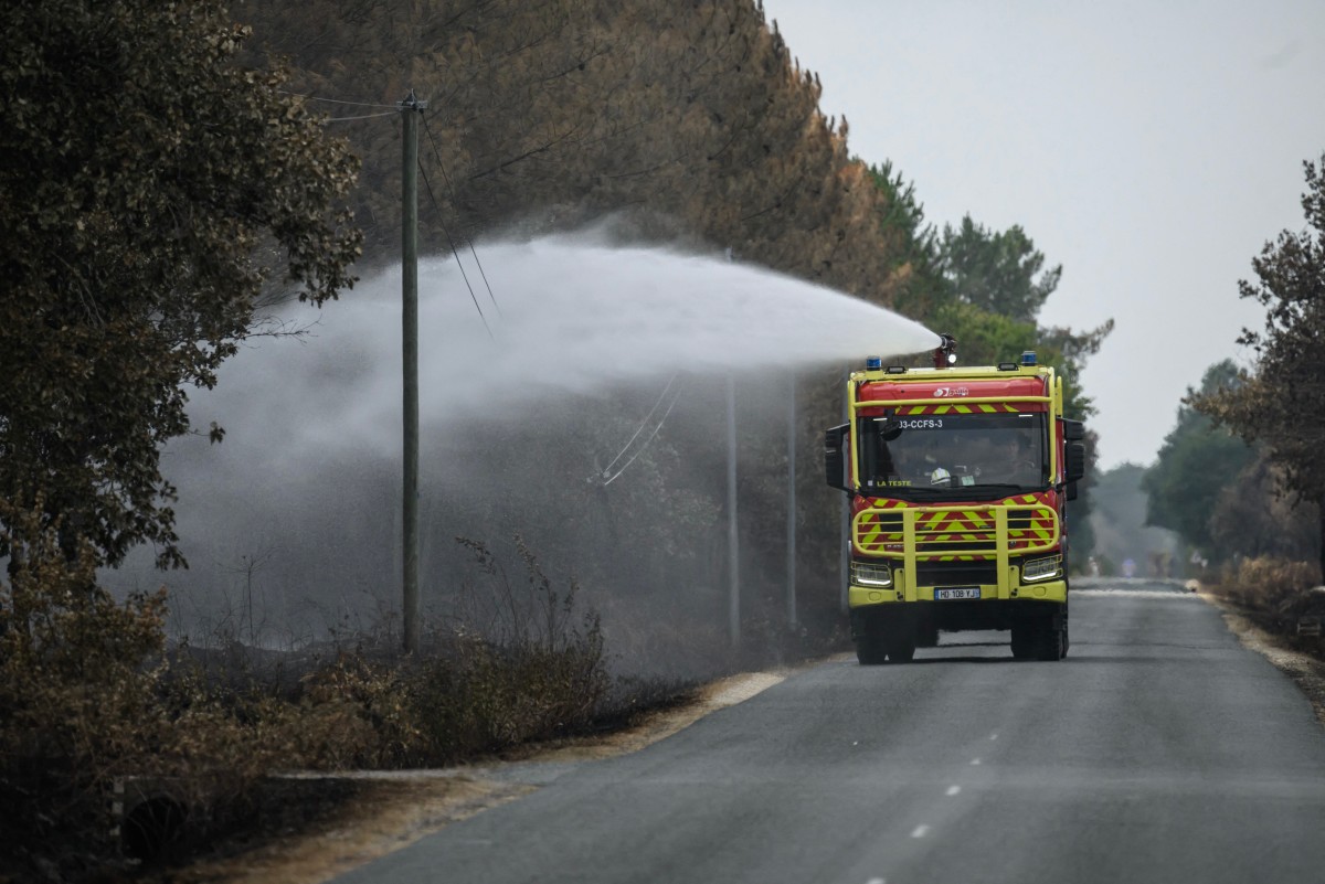 Bombeiros lançam água enquanto combatem pequenos focos de incêndio em uma floresta perto de Blagon, no sudoeste da França, em 30 de julho de 2026. A França tem sido castigada por três ondas de calor desde maio — parte de episódios de clima extremo cada vez mais frequentes associados às mudanças climáticas —, o que tem provocado um excesso de mortes, secado rios e alimentado incêndios florestais.