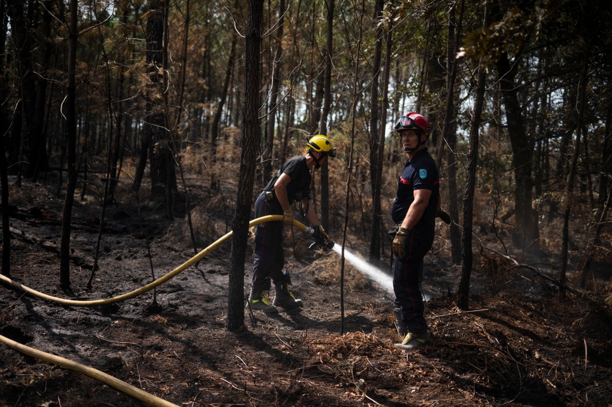Bombeiros apagam focos de incêndio remanescentes após um incêndio florestal em Andernos-les-Bains, no sudoeste da França, em 30 de julho de 2026. Na França, as temperaturas caíram perto de Bordeaux, a capital do vinho, gerando esperanças de que o incêndio em uma floresta de pinheiros à beira-mar — que desalojou 220.000 pessoas e destruiu cerca de 240 casas — estivesse chegando ao fim.