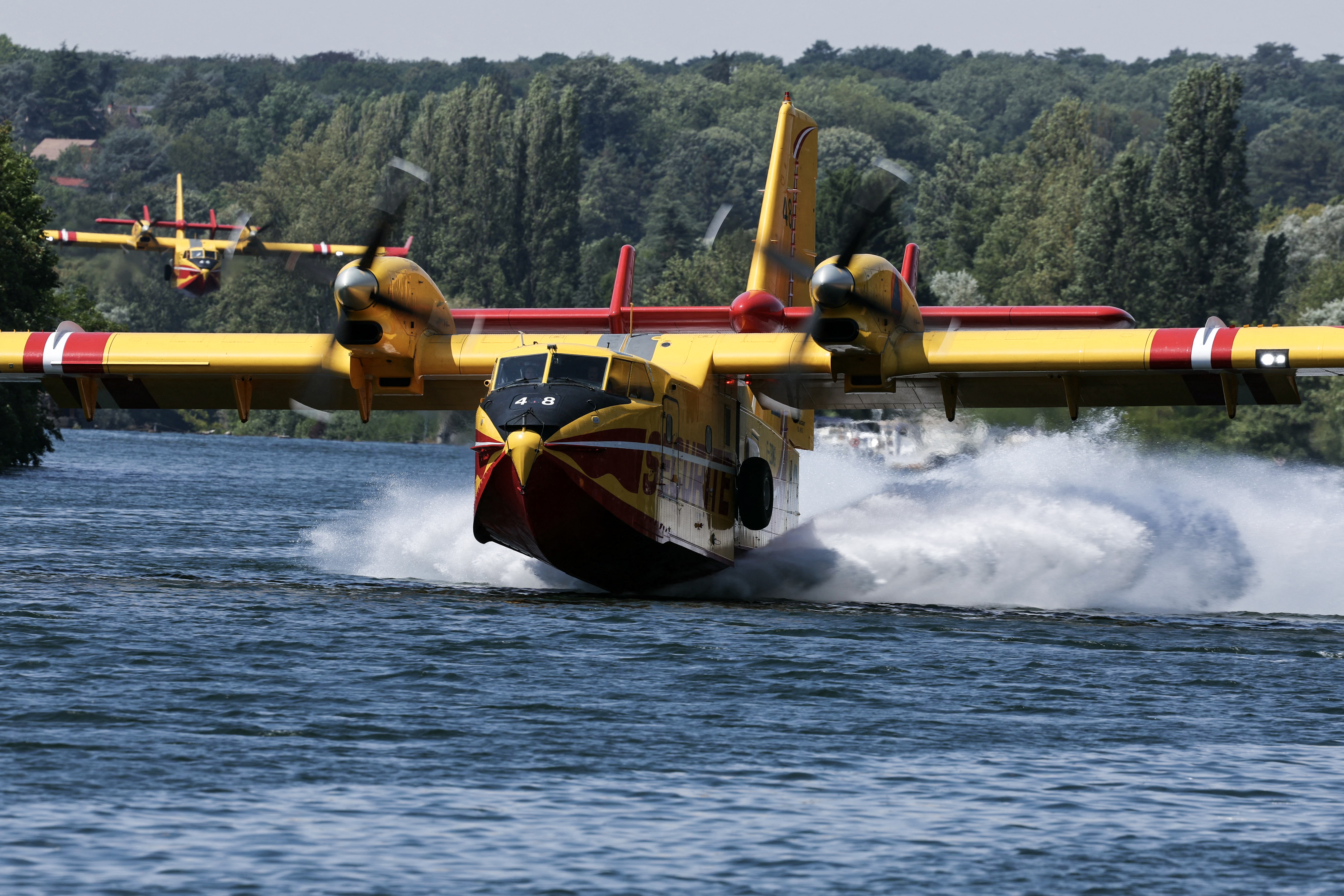 Aeronaves Canadair CL-415 da Defesa Civil francesa realizam manobras de captação de água ao rasar a superfície do rio Sena em Chartrettes, na região de Île-de-France (arredores de Paris), em 13 de julho de 2026, após o incêndio na Floresta de Fontainebleau.