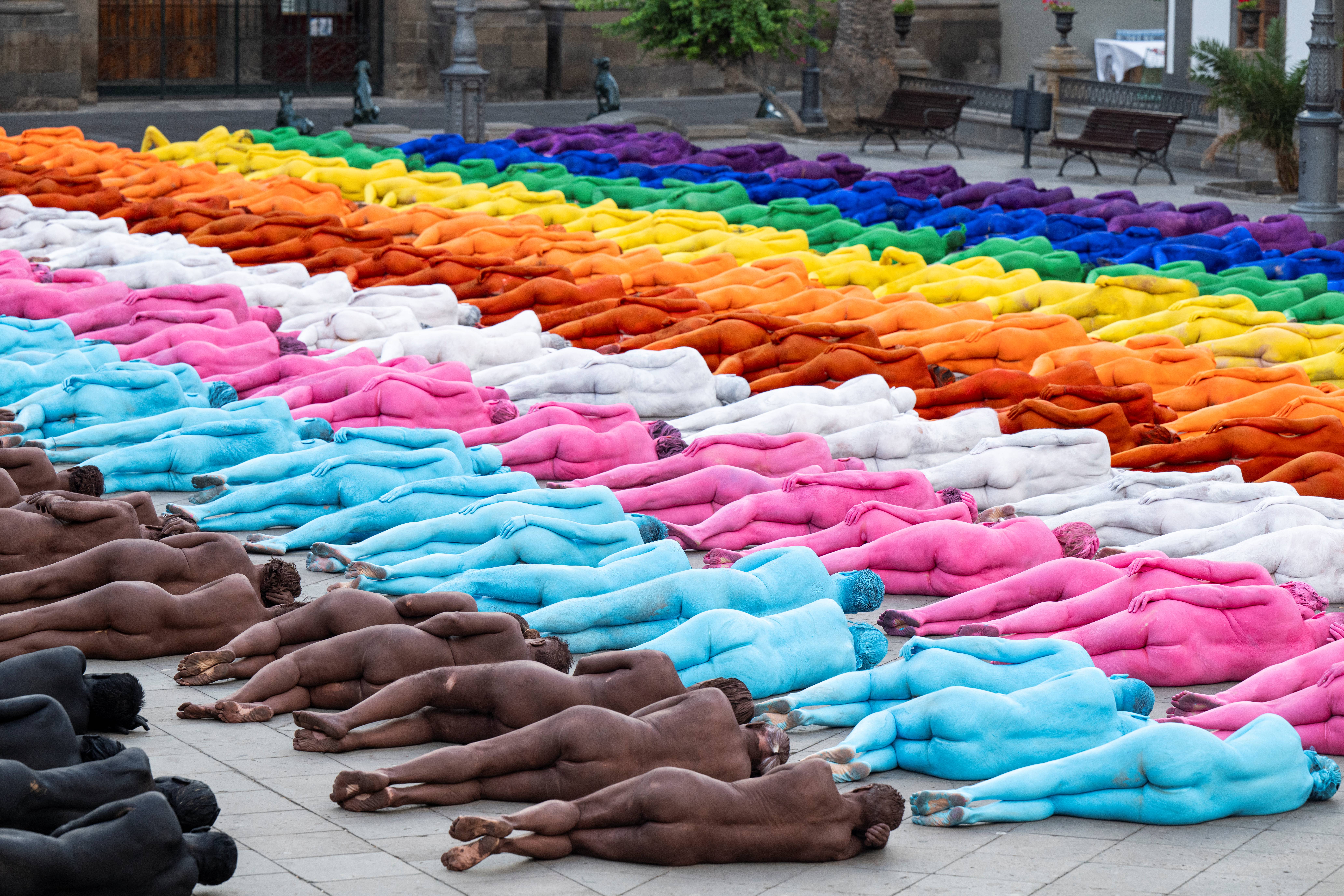 Participantes posam nus e com o corpo pintado enquanto o fotógrafo americano Spencer Tunick faz registros de sua intervenção artística coletiva "Grand Spectrum" na praça Santa Ana, no bairro de Vegueta, em Las Palmas de Gran Canaria, em 26 de julho de 2026.