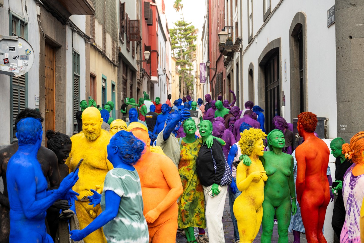 Participantes nus e com o corpo pintado posam juntos após serem fotografados pelo americano Spencer Tunick (não aparece na imagem) para sua intervenção artística coletiva "Grand Spectrum", na praça Santa Ana, no bairro de Vegueta, em Las Palmas de Gran Canaria, em 26 de julho de 2026.