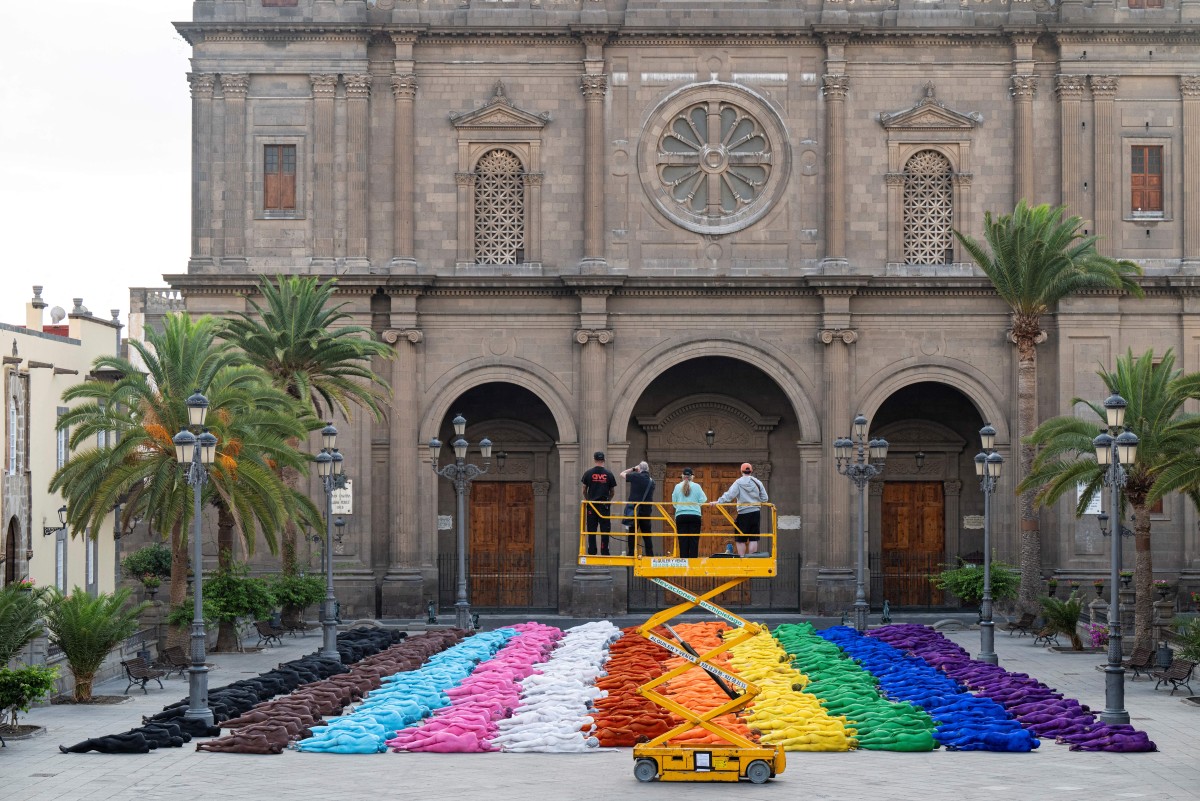 Participantes posam nus e com o corpo pintado enquanto o fotógrafo americano Spencer Tunick faz registros de sua intervenção artística coletiva "Grand Spectrum" na praça Santa Ana, no bairro de Vegueta, em Las Palmas de Gran Canaria, em 26 de julho de 2026.