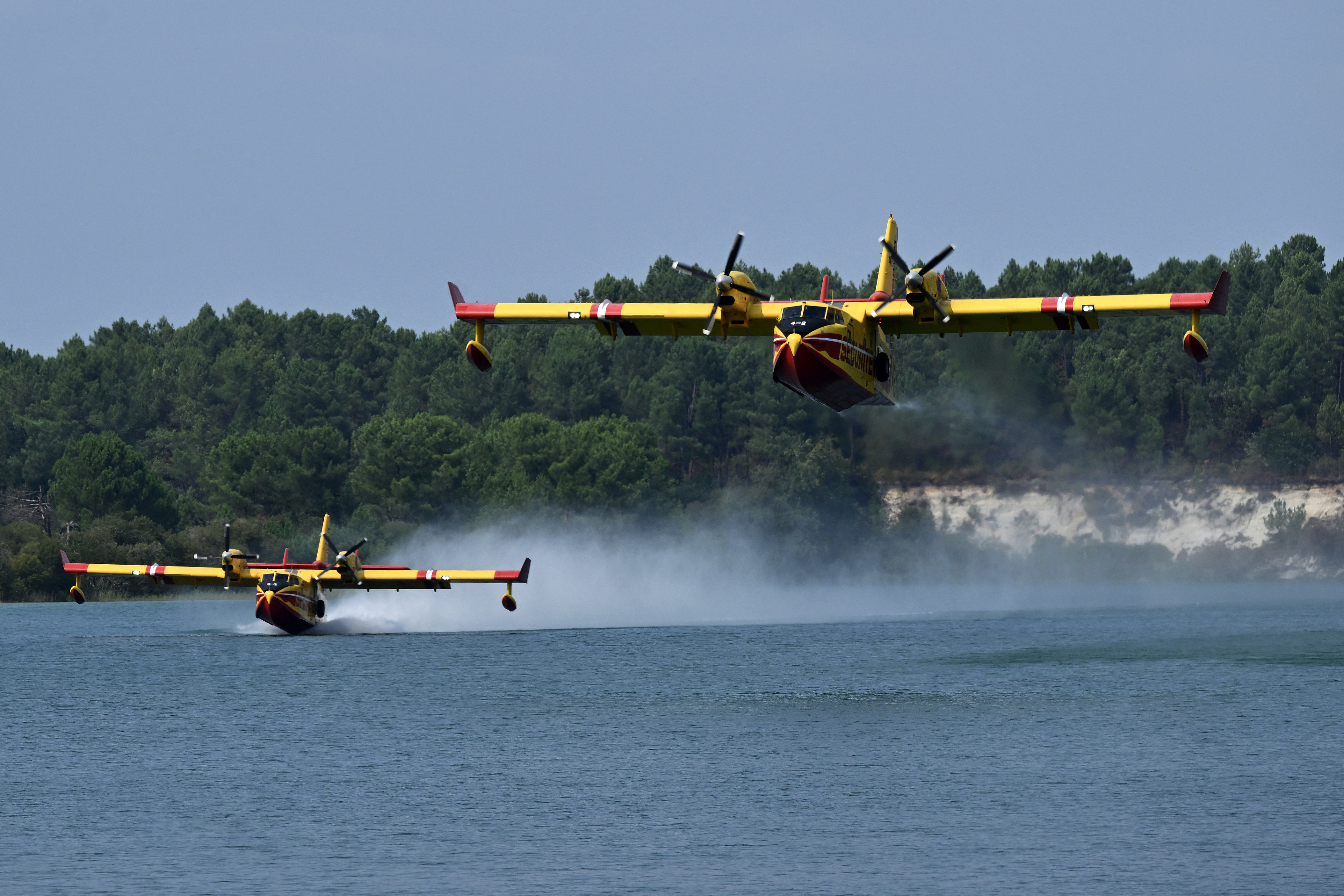 Aeronaves de combate a incêndios Canadair CL-415 da Segurança Civil francesa decolam do Lago Arjuzanx após o lançamento de água durante um incêndio florestal na floresta de Landes, em Arjuzanx, no sudoeste da França