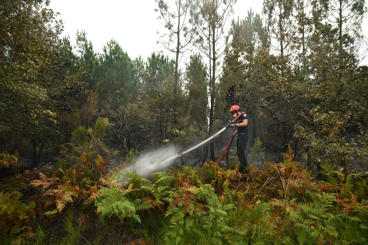Um bombeiro joga água em uma floresta durante um incêndio florestal em Luglon, no sudoeste da França