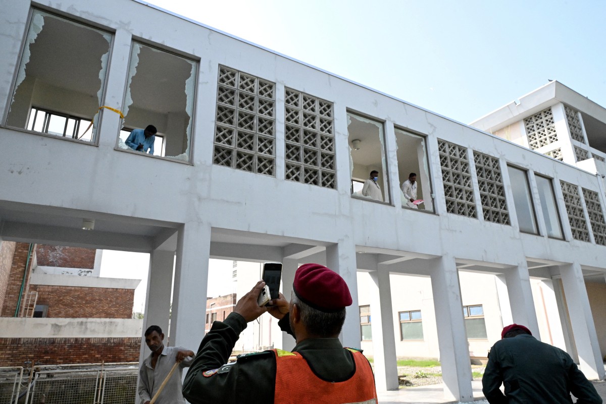 Trabalhadores removem cacos de janelas quebradas após um incêndio na ala de Saúde Materno-Infantil (MCH) do Hospital do Instituto de Ciências Médicas do Paquistão (PIMS), em Islamabad, em 26 de agosto de 2026.