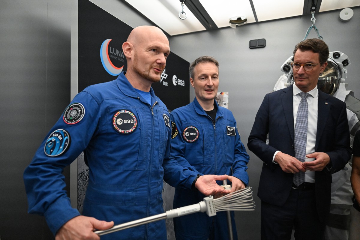 Os astronautas alemães Alexander Gerst (à esquerda) e Matthias Maurer (ao centro) participam de um evento para a imprensa com o ministro-presidente da Renânia do Norte-Vestfália, Hendrik Wuest (à direita), na nova instalação de simulação lunar LUNA, situada no campus do Centro Aeroespacial Alemão (DLR).