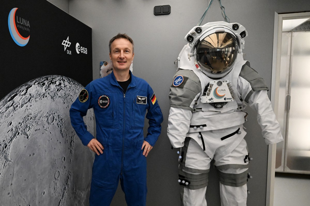 O astronauta alemão Matthias Maurer posa para fotos ao lado de um traje espacial durante um evento de imprensa na nova instalação de simulação lunar LUNA, no campus do Centro Aeroespacial Alemão (DLR), próximo ao Centro Europeu de Astronautas da Agência Espacial Europeia (ESA), em Colônia-Porz, no oeste da Alemanha, em 3 de setembro de 2026.
