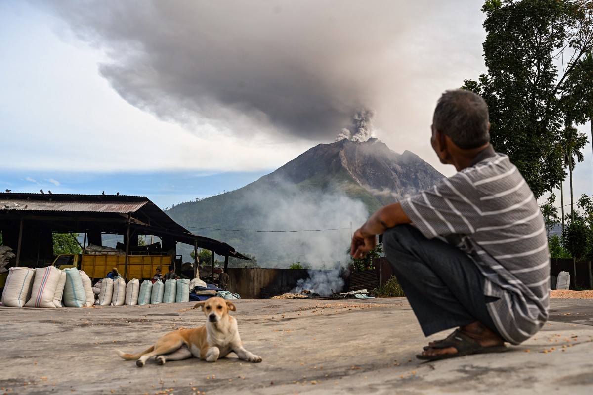 Um homem observa o Monte Sinabung expelindo cinzas e fumaça densa, visto de Karo, na província de Sumatra do Norte, na manhã de 2 de setembro de 2026.