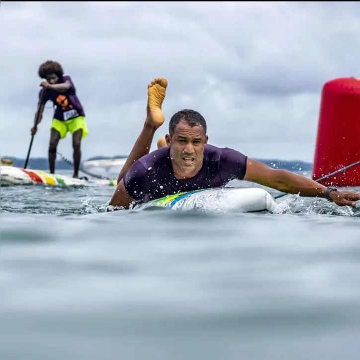 Jader, à frente, praticando paddleboard, enquanto outro atleta, ao fundo, pratica stand-up paddle