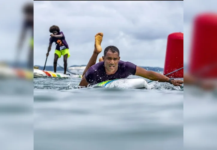 Jader, à frente, praticando paddleboard, enquanto outro atleta, ao fundo, pratica stand-up paddle