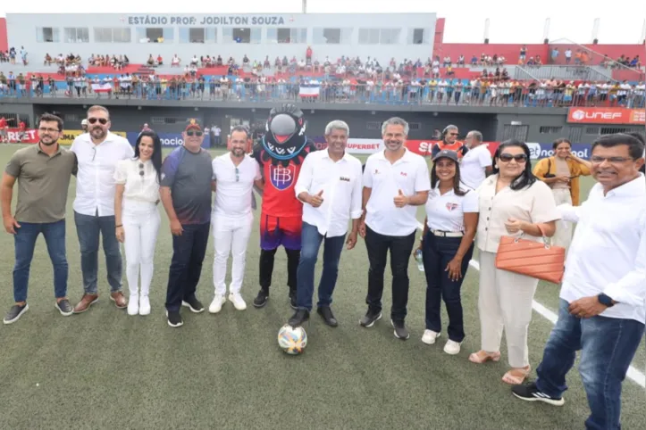 Mascote do Baianão ao centro com Jerônimo Rodrigues em seu lado esquerdo e Ricardo Lima, presidente da FBF, em seu lado direito