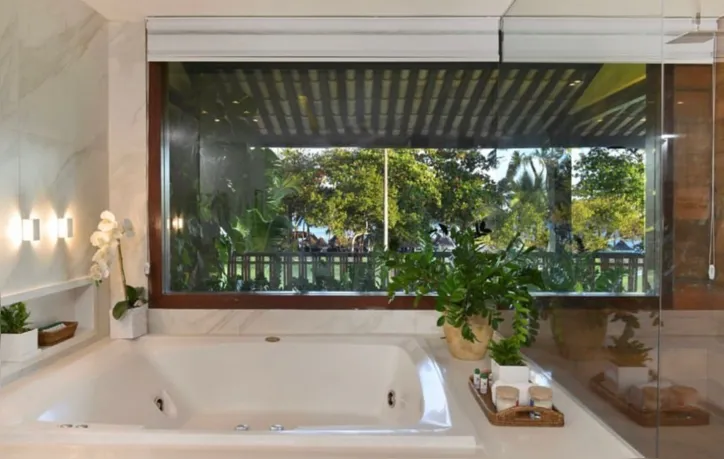Banho com hidromassagem ornamentado de verde em ambiente cercado de vidro