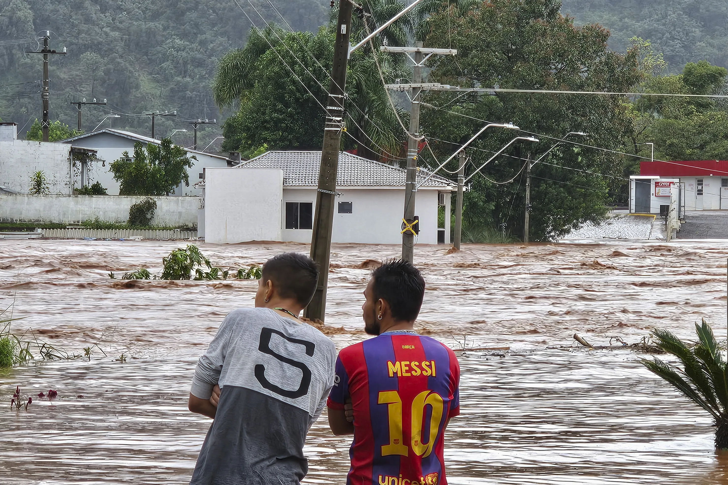 People observe a flooded street after heavy rains in Encantado, Rio Grande do Sul, Brazil on May 1, 2024. At least ten people died and 21 are missing due to heavy rains in the southern Brazilian state of Rio Grande do Sul, authorities said Wednesday. (Photo by Gustavo Ghisleni / AFP)