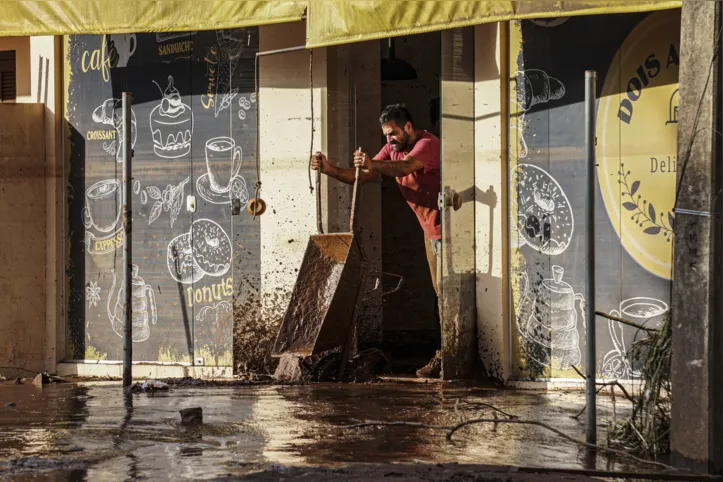 A man removes the mud left by floods from a store in Roca Sales, Rio Grande do Sul state, Brazil, on May 5, 2024. Authorities in southern Brazil scrambled Sunday to rescue people from raging floods and mudslides in what has become the region's largest ever climate catastrophe, with at least 78 dead and 115,000 forced from their homes. (Photo by Gustavo Ghisleni / AFP)