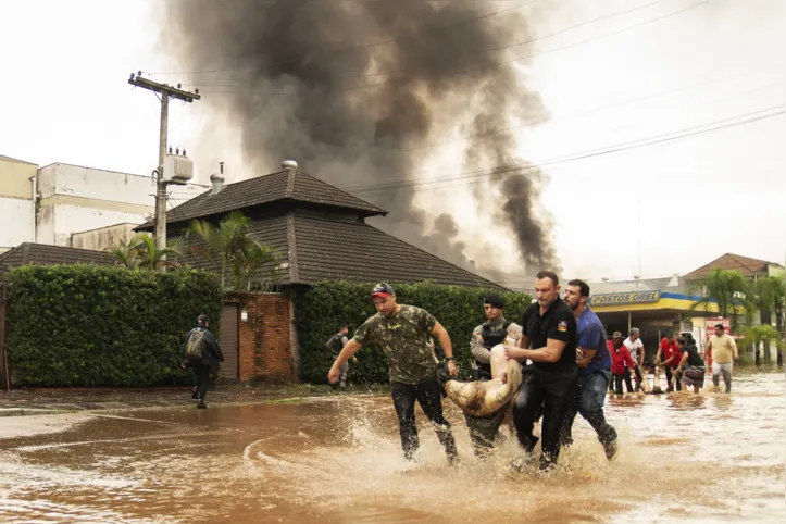 EDITORS NOTE: Graphic content / People and policemen carry the body of a victim after an explosion at a petrol station in Porto Alegre, Rio da Grande do State, Brazil on May 4, 2024. The floods caused by the intense rains that hit southern Brazil left at least 56 dead and 67 missing, according to a new report on Saturday from Civil Defense. (Photo by Carlos FABAL / AFP)