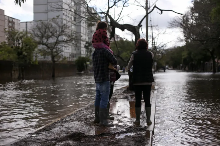 Residents wait to cross a flooded street in Porto Alegre, Rio Grande do Sul, Brazil on May 26, 2024. The southern state of Rio Grande do Sul is reeling from weeks of unprecedented floods that have left more than 160 people dead, some 100 missing and left 90 percent of its towns inundated, including the state capital, Porto Alegre. (Photo by Anselmo Cunha / AFP)