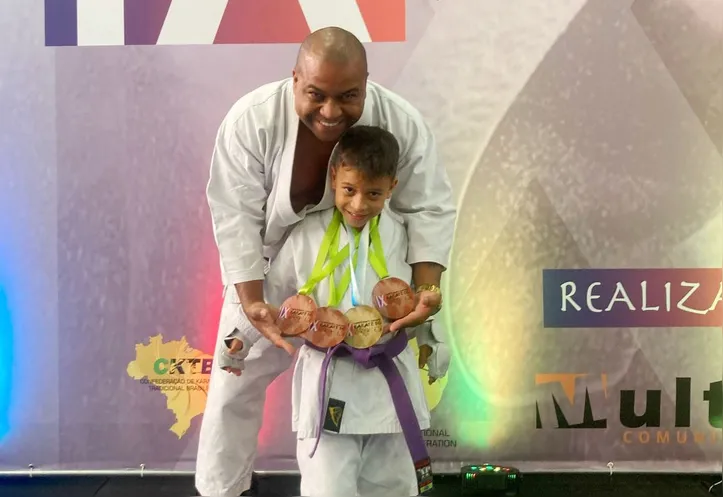 O pequeno Gabriel Oliveira das Neves celebra as medalhas ao lado do pai e treinador, Paulo Tuchê