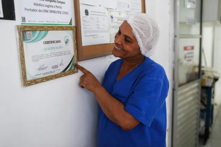 Orgulhosa, Márcia mostra o certificado do curso de tanatoplaxia pendurado na parede da empresa