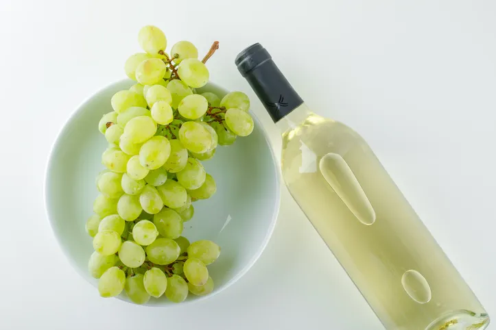 Green grapes with wine in a plate on white background, top view.