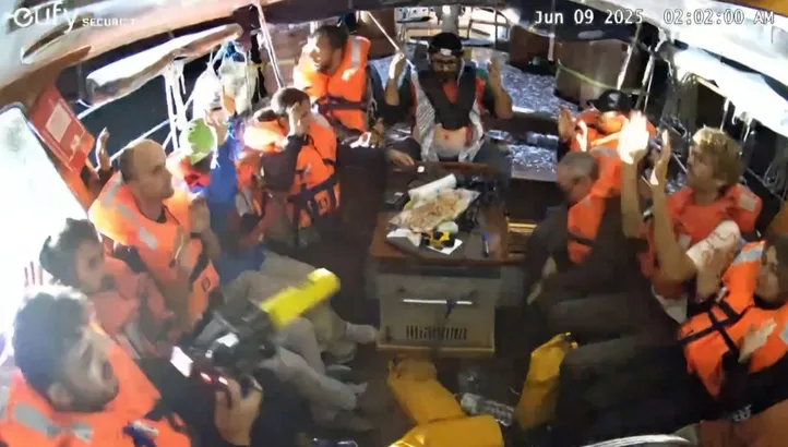 An image grab from footage released by Freedom Flotilla Coalition on June 9, 2025 shows activists on board the Gaza-bound aid boat Madleen, with their hands in the air, as they are being intercepted by the Israeli forces in international waters before reaching the blockaded Palestinian territory. The boat was redirected to Israel's shores, preventing the activists onboard, including Swedish campaigner Greta Thunberg and European parliament member Rima Hassan, from reaching the Gaza Strip. (Photo by Freedom Flotilla Coalition / AFP) / RESTRICTED TO EDITORIAL USE - MANDATORY CREDIT "AFP PHOTO / FREEDOM FLOTILLA COALITION " - NO MARKETING NO ADVERTISING CAMPAIGNS - DISTRIBUTED AS A SERVICE TO CLIENTS