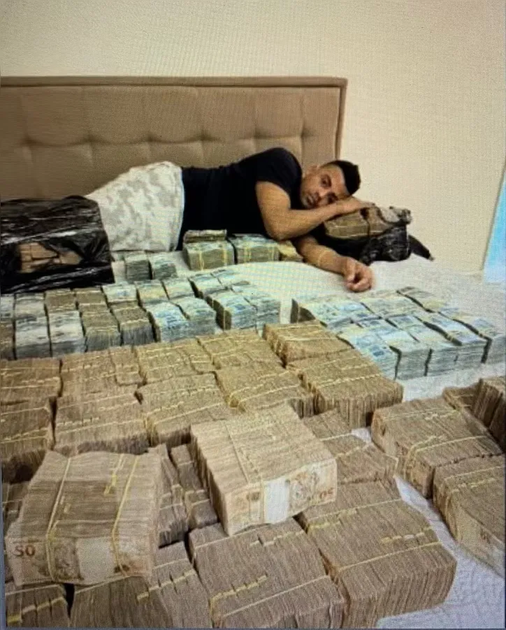 TH Joias deitado numa cama com maços de reais