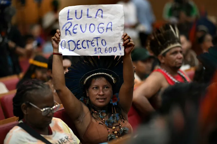 Indígena segura uma placa com os dizeres "Lula revogue o decreto 12600, que criou o Plano Nacional de Hidrovias
