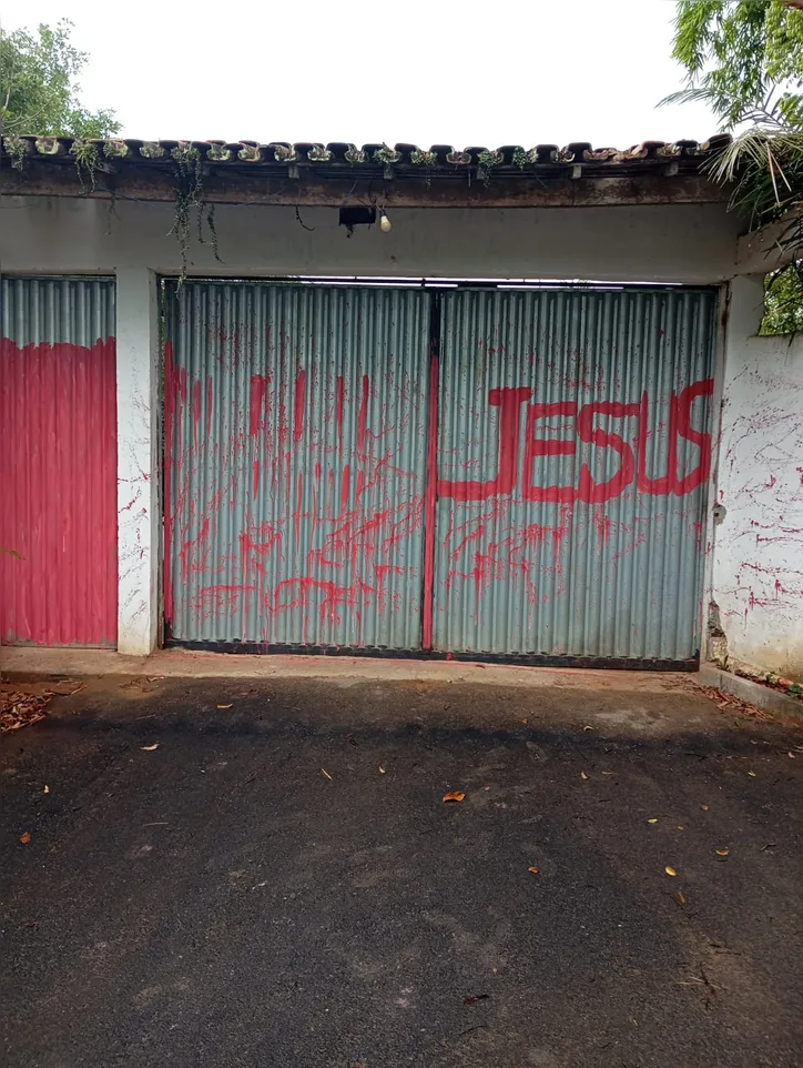 O portão de pedestre foi pintado de vermelho e a palavra Jesus foi pichada no portão da garagem