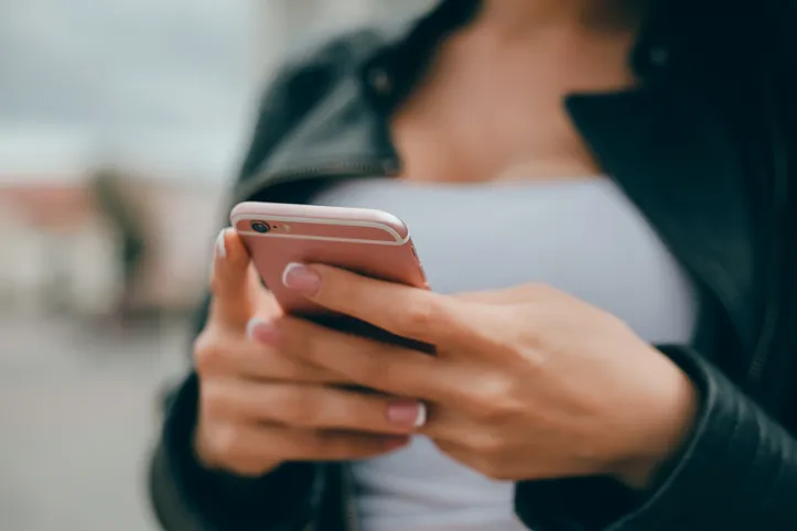 young beautiful girl uses a smartphone on the street, surfing in internet