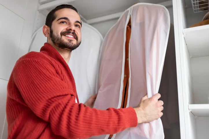 Homem guardando roupa em saco de TNT